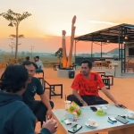 Pengunjung menikmati kopi di Kafe Sawah Sebelas 12 diantara siluet senja yang jatuh perlahan di balik hamparan sawah.